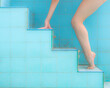 Leg and hand of woman in a ballerina tiptoe position, ascending on a pool steps