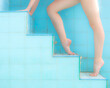 Legs of woman in a ballerina tiptoe position, ascending on a pool steps