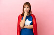 © luismolinero - Super Hero redhead girl isolated on pink background having doubts and with confuse face expression