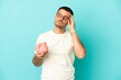 © luismolinero - Brazilian man holding a piggybank over isolated blue background with headache