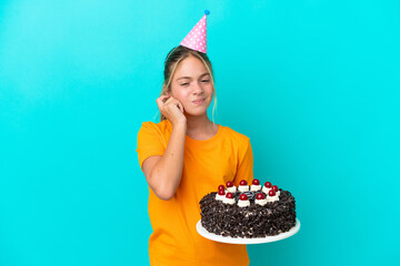 Wall Mural - Little caucasian girl holding birthday cake isolated on blue background frustrated and covering ears