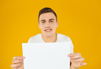 Wall Mural - Cheerful man in white t-shirt sheet of paper copy space advertisement