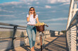 Young pretty woman walking with bike and talking on cell