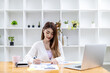 © kamiphotos - A beautiful Asian businesswoman sitting in her private office, she is checking company financial documents, she is a female executive of a startup company. Concept of financial management.