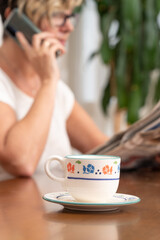 Wall Mural - Selective focus shot of a coffee cup in front of a Caucasian woman talking on the phone