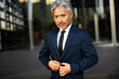 © Jelena - Portrait of senior businessman with crossed arms. Handsome man in suit outdoors.