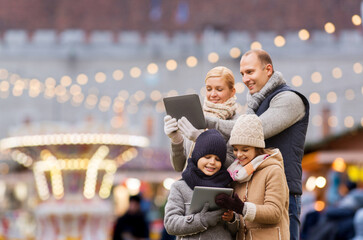 Poster - winter holidays, leisure and people concept - happy family with tablet pc computers over christmas market or amusement park background