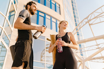 Young man and woman drinking water while working out together