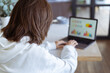 © Анастасия Каргаполов - Young woman at home in the kitchen in a white hoodie with a laptop, advisor financial business analytics woman with data dashboard graphs