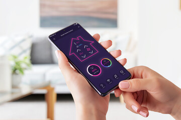 Poster - Modern smart home control app on smart phone concept. Woman holding smart phone and controle temperature, light, music and security system