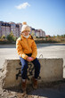 © Анна Молько - sad girl in a yellow jacket sits on a concrete slab against the backdrop of the autumn city.