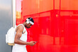 © ADDICTIVE STOCK - Black man in headphones browsing smartphone in street