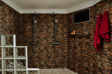 Poster - Shot of the interior of a shower room with a Tv and red towels on brown textured walls