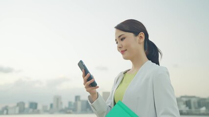 Aufkleber - 都市を背景にスマホを見る女性