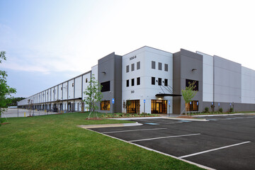 Modern gray industrial warehouse distribution building and parking lot