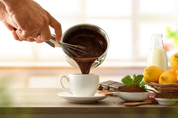 Man filling a cup of fresh hot chocolate from saucepan