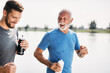Happy senior athletic man and his son enjoy in jogging by lake.