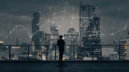 Wall Mural - Businessman standing using smartphone in modern space watching city night view.Business Wireless network and Connection technology concept.