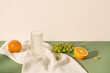 Still life with grapes, orange and water on tablecloth.