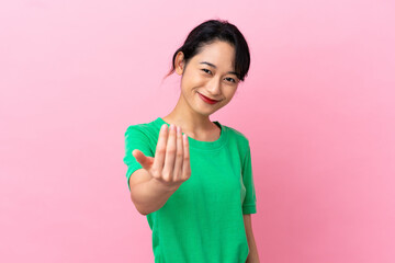 Wall Mural - Young Vietnamese woman isolated on pink background inviting to come with hand. Happy that you came