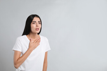 Canvas Print - Young woman suffering from breathing problem on light background. Space for text