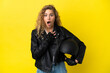 © luismolinero - Young blonde woman with a motorcycle helmet isolated on yellow background surprised and shocked while looking right