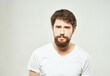 © SHOTPRIME STUDIO - bearded man in a white t-shirt irritated facial expression light background