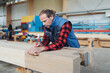 © contrastwerkstatt - Male carpenter measuring a wooden beam with a right angle