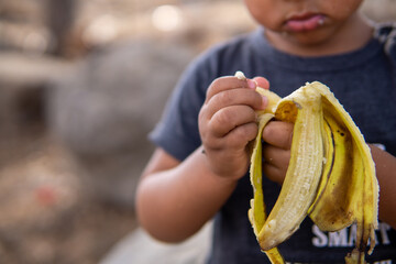 ehiopian toddler mixed ethnicty interracial kid peeling yellow banana portrait in israel with copy space happy baby eating banana isolated on the black