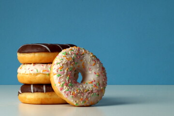 A beautiful turret of three delicious fresh donuts with different colored sprinkles and chocolate. One donut is lying sideways.