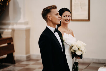 Beautiful shot of a Caucasian (white) bride and groom together in the church in Lithuania