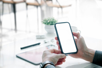 Wall Mural - man hamd holding blank white screen smartphone while sitting at desk office.