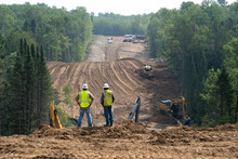 CASS CO, MN - 6 AUG 2021: Enbridge Line 3 Oil Pipeline Construction Site In Minnesota Forest With Excavators And Bulldozers Covering The Installed Pipe. Foreground Is Intentionally Out Of Focus.