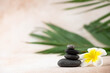 Pyramids of gray and white zen pebble meditation stones on beige background with plumeria tropical flower. Concept of harmony, balance and meditation, spa, massage, relax