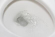 Motion Blur Of Flushing Water In Toilet Bowl. Plumbing, Home Repair And Water Conservation Concept.