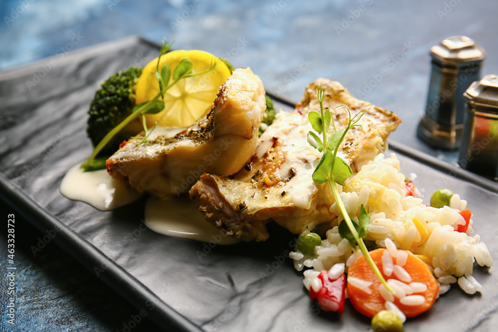 Plate with delicious baked cod fillet, rice and vegetables on color background, closeup