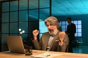 Poster - Happy mature businessman working with laptop in office at night