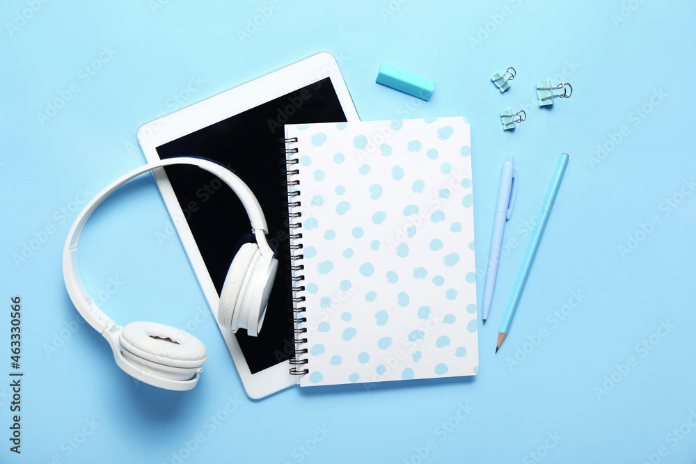 Stationery supplies, headphones and tablet computer on color background