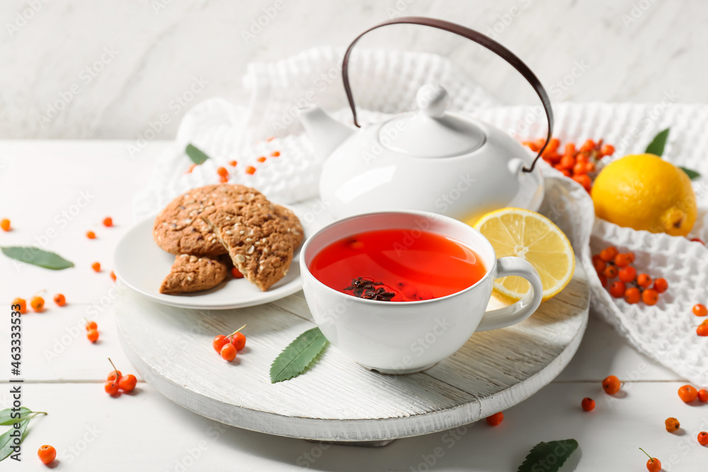 Composition with cup of rowan tea and cookies on table