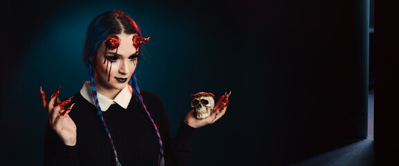 Fototapeta woman with scary halloween makeup with bloody horns dark background