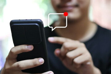 Person using a social media marketing concept on mobile phone with notification icons of like, message, comment and star above smartphone screen.