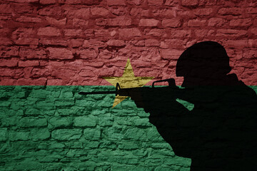 Wall Mural - Soldier silhouette on the old brick wall with flag of burkina faso country.
