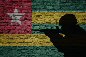 Wall Mural - Soldier silhouette on the old brick wall with flag of togo country.