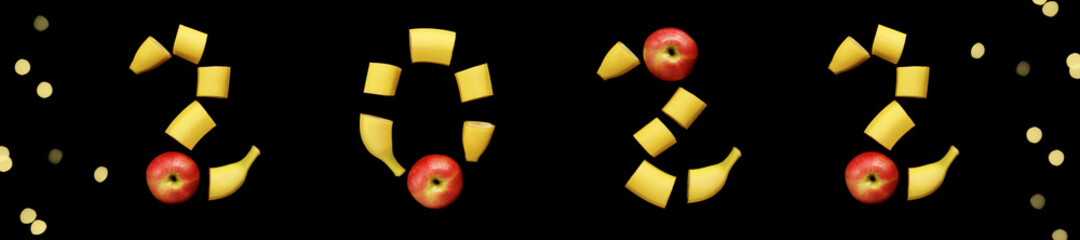 Banner of the coming new year 2022 numbers laid out on a black background from a yellow cut banana and a red apple, festive bokeh from a garland on the sides, fruit composition, flat lay, copy space.