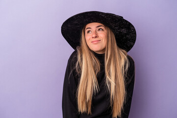 Wall Mural - Young Russian woman disguised as a witch celebrating Halloween isolated on purple background dreaming of achieving goals and purposes