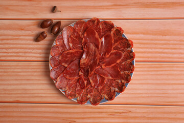 Wall Mural - Portion of 100% acorn-fed Iberian loin on wooden table, adorned with acorns