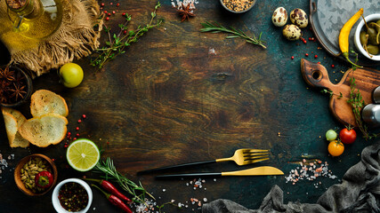 Cutlery on a black stone table with vegetables and spices. Food background. Top view. Rustic style.