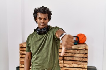 Sticker - African man with curly hair wearing sportswear at the gym looking unhappy and angry showing rejection and negative with thumbs down gesture. bad expression.