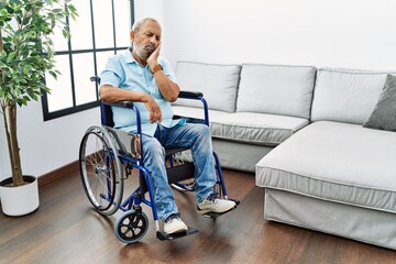 Poster - Handsome senior man sitting on wheelchair at the living room thinking looking tired and bored with depression problems with crossed arms.