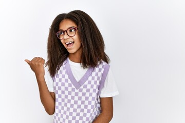 Sticker - Young african american girl standing over isolated background smiling with happy face looking and pointing to the side with thumb up.